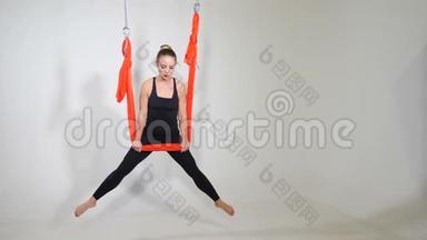 年轻的微笑运动的女人挂在吊床上做瑜伽。 生活方式和运动。 空中瑜伽。 漂亮的女运动员